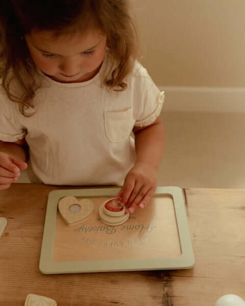 Criança usando o Conjunto de Pasteleiro Little Dutch para fazer bolachas de brincar.