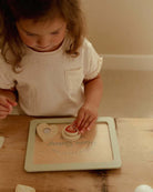 Criança usando o Conjunto de Pasteleiro Little Dutch para fazer bolachas de brincar.