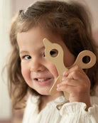 Conjunto de Cabeleireiro Little Dutch, menina segurando brinquedo de cortar cabelo em madeira.