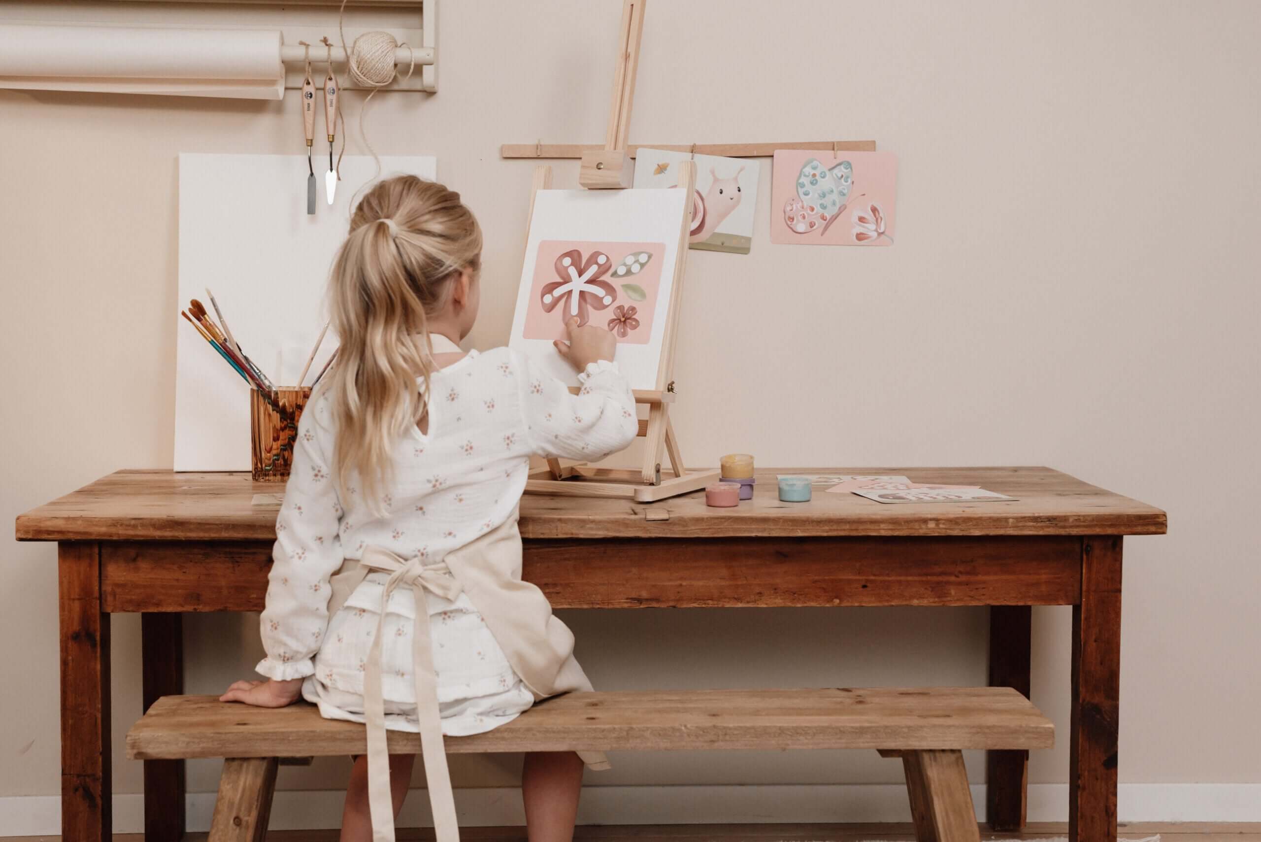 Little girl painting at a wooden table, using the Little Dutch Fairy Garden Finger Painting Set.