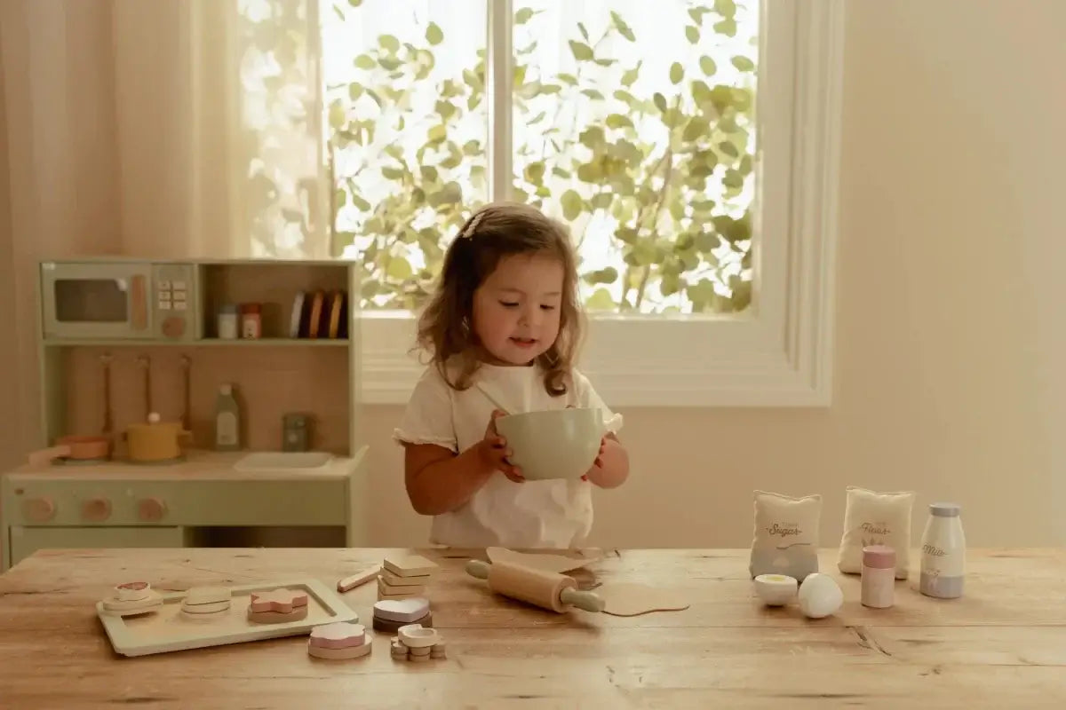 Conjunto de Pasteleiro Little Dutch: criança segurando uma tigela em cozinha de brinquedo com ingredientes.