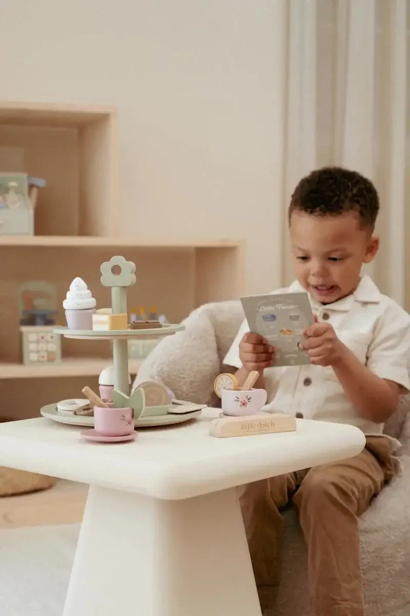 Criança brincando com a Bandeja de Bolos Little Dutch, organizando chá com doces e menu ilustrado.
