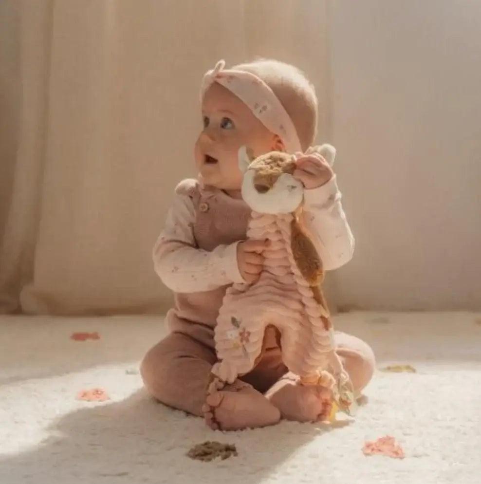 Baby sitting on a soft rug, happily holding a plush deer toy from the Little Dutch Fairy Garden collection.