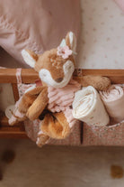 Soft Little Dutch Fairy Garden deer plush toy with a flower on its head, draped over a crib with rolled blankets.