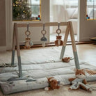 Play gym with hanging toys and soft mat featuring Forest Friends design, perfect for baby playtime and comfort.