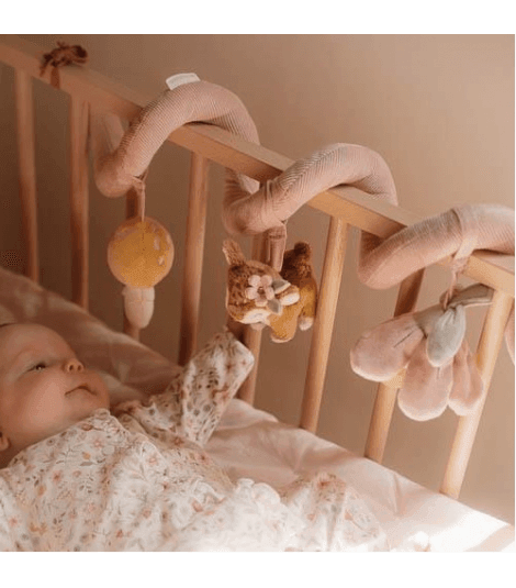 Baby exploring the Little Dutch Fairy Garden activity spiral in a crib, featuring soft toys and vibrant colors.