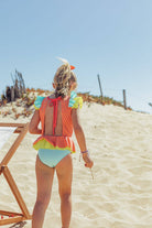 Menina usando fato de banho Candy Colors da Paper Boat na praia, destacando design colorido e confortável.