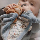 Baby holding soft Little Dutch Raposinha cuddle toy with floral pattern, enjoying comfort and warmth.