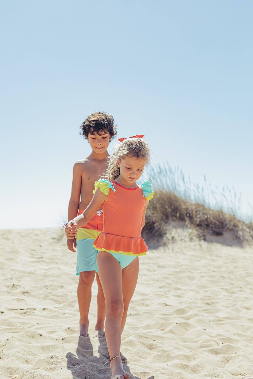Two children playing on the beach, girl in Paper Boat's Candy Colors swimsuit designed in Portugal with high-quality materials