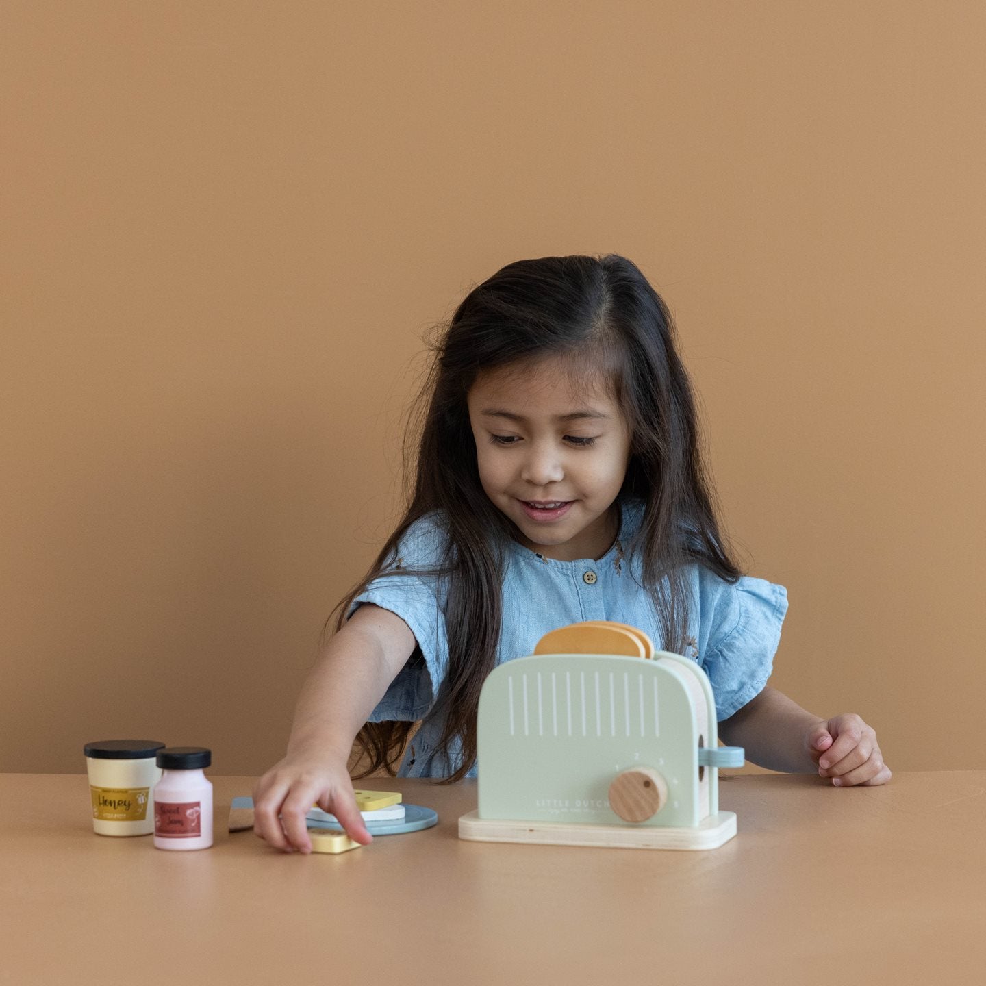 Criança brincando com a torradeira de madeira Little Dutch em um ambiente divertido e educativo.